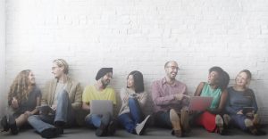 Group of people sitting down against a wall laughing